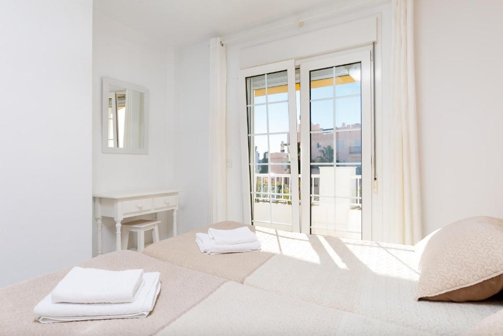 a white bedroom with a bed with towels on it at AT Almoraide Rooms Suites in Nerja