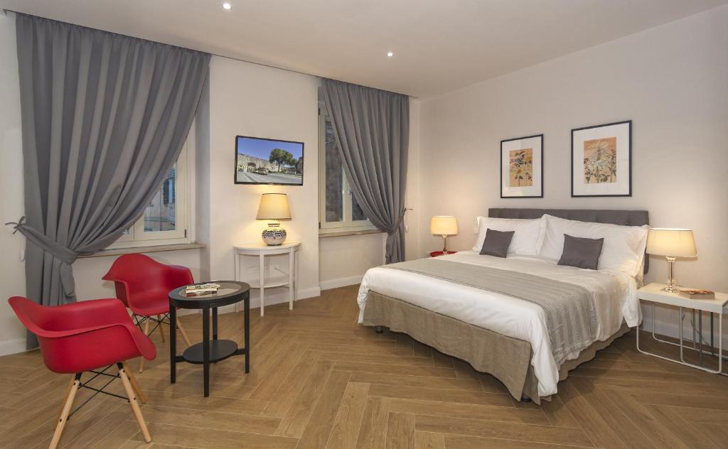 ピサにあるIl Giardino Dei Sempliciのベッドと赤い椅子が備わるホテルルームです。