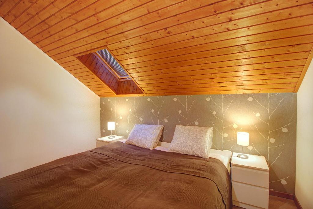ein Schlafzimmer mit einem großen Bett und einer Holzdecke in der Unterkunft Apartments Nový Život in Nový Život