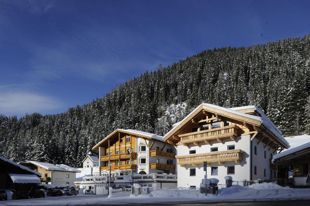 un grand bâtiment dans la neige avec une montagne dans l'établissement Gasthof Burkert, à Oetz