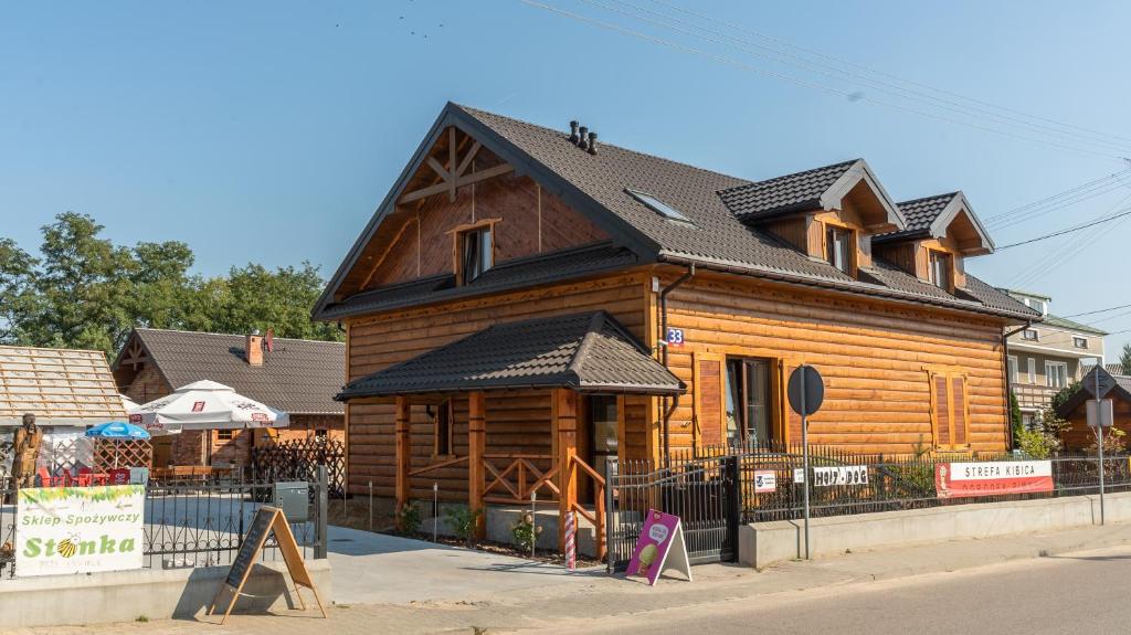 uma grande casa de madeira com um telhado preto em Pokoje Gościnne Nad Wkra em Joniec
