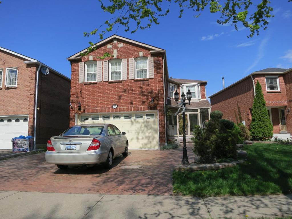 un coche aparcado frente a una casa de ladrillo en All Seasons Bed & Breakfast, en Mississauga