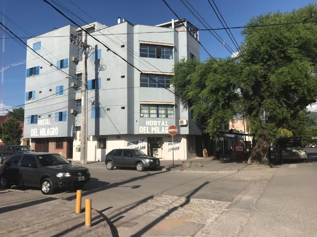 un edificio bianco con auto parcheggiate di fronte di Hostal del Milagro a Salta