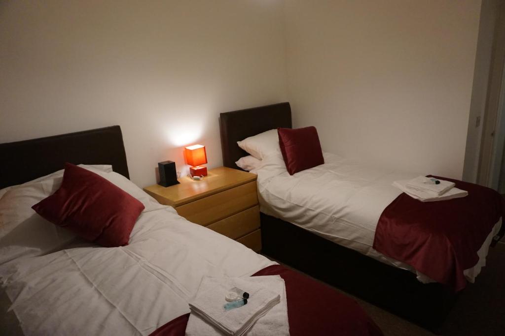 two beds in a room with a lamp on a night stand at The Coach House in Bristol