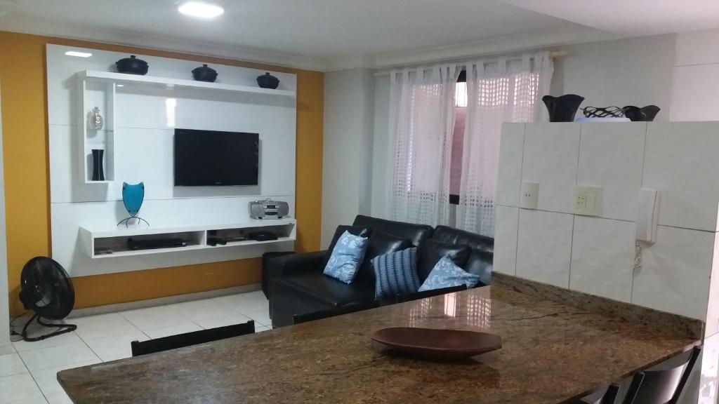 a living room with a black couch and a television at Ótimo apartamento com wi-fi gratuito in Guarapari