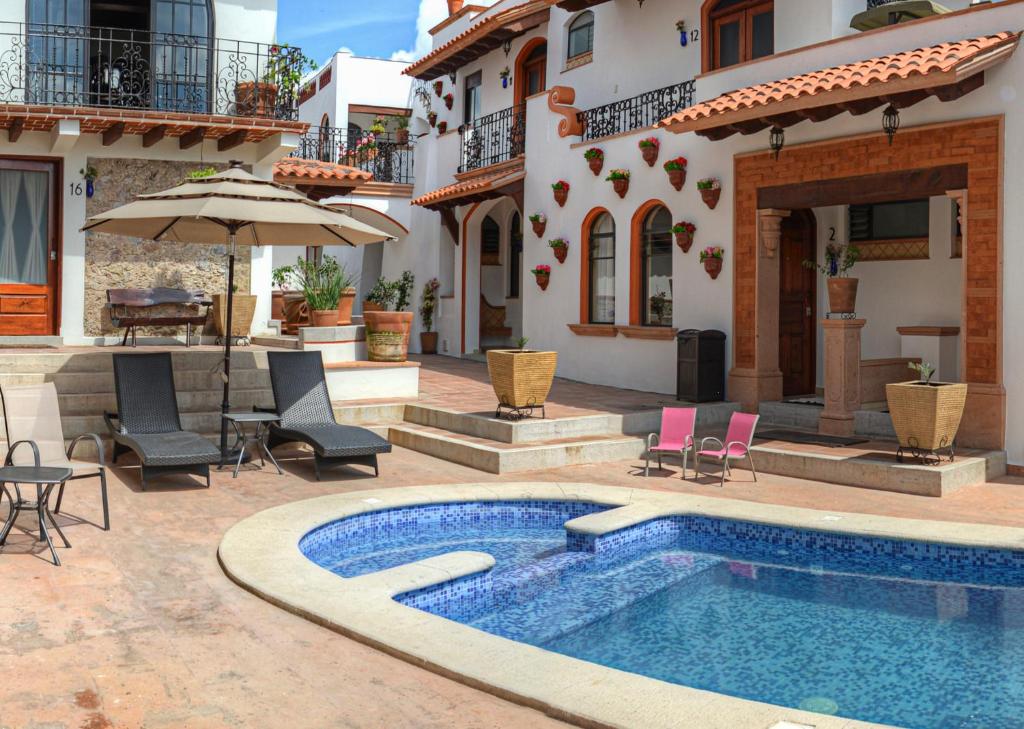 a swimming pool with a patio area with chairs and umbrellas at Hotel Santa Paula in Taxco de Alarcón