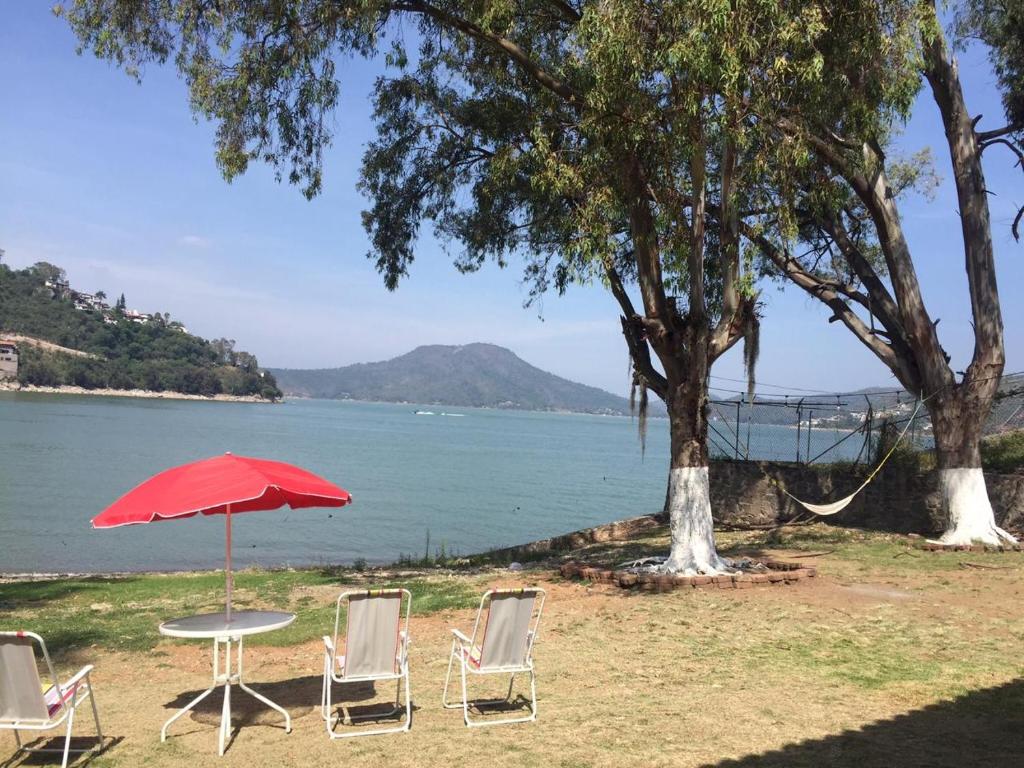 two chairs and a table with an umbrella next to the water at Don Polo casaboutique in Valle de Bravo