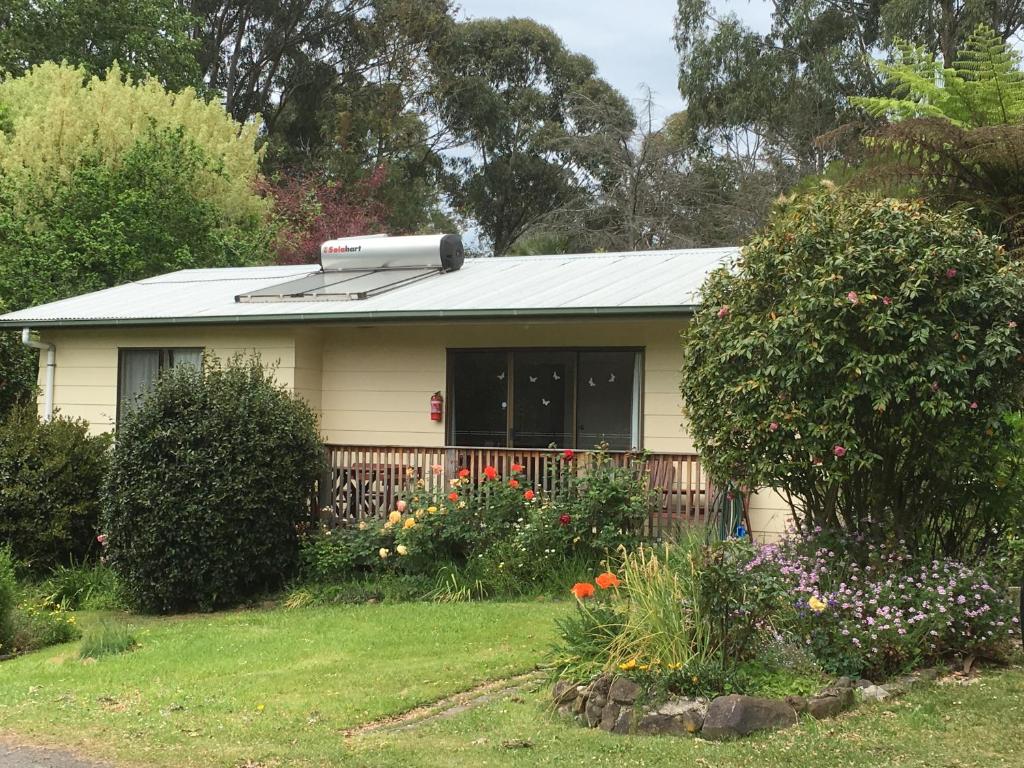 a small yellow house with a roof and flowers at Strathmore Farm B&B in Mirboo North