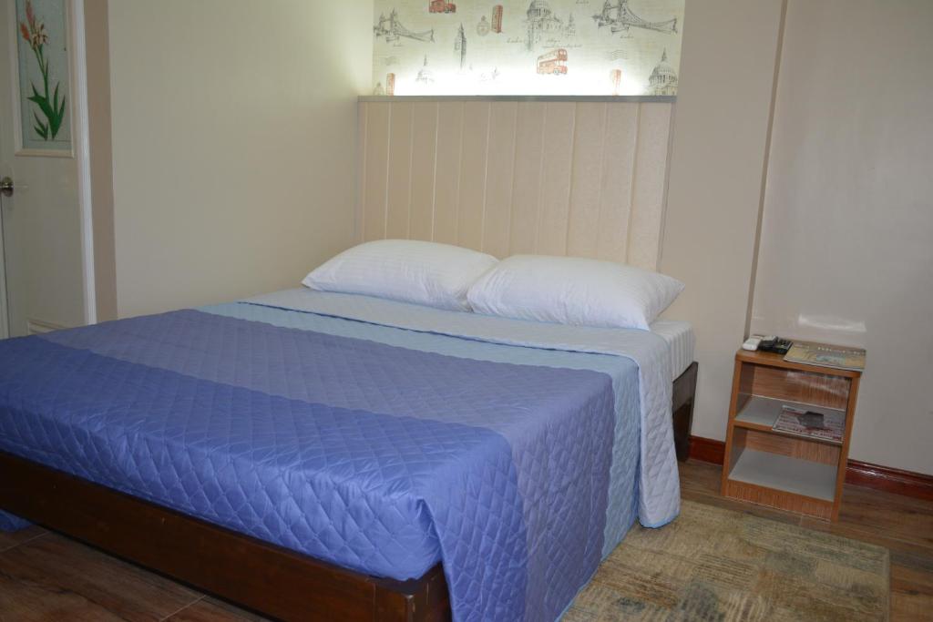 a bedroom with a bed with a blue comforter at Red Apartelle in Talisay