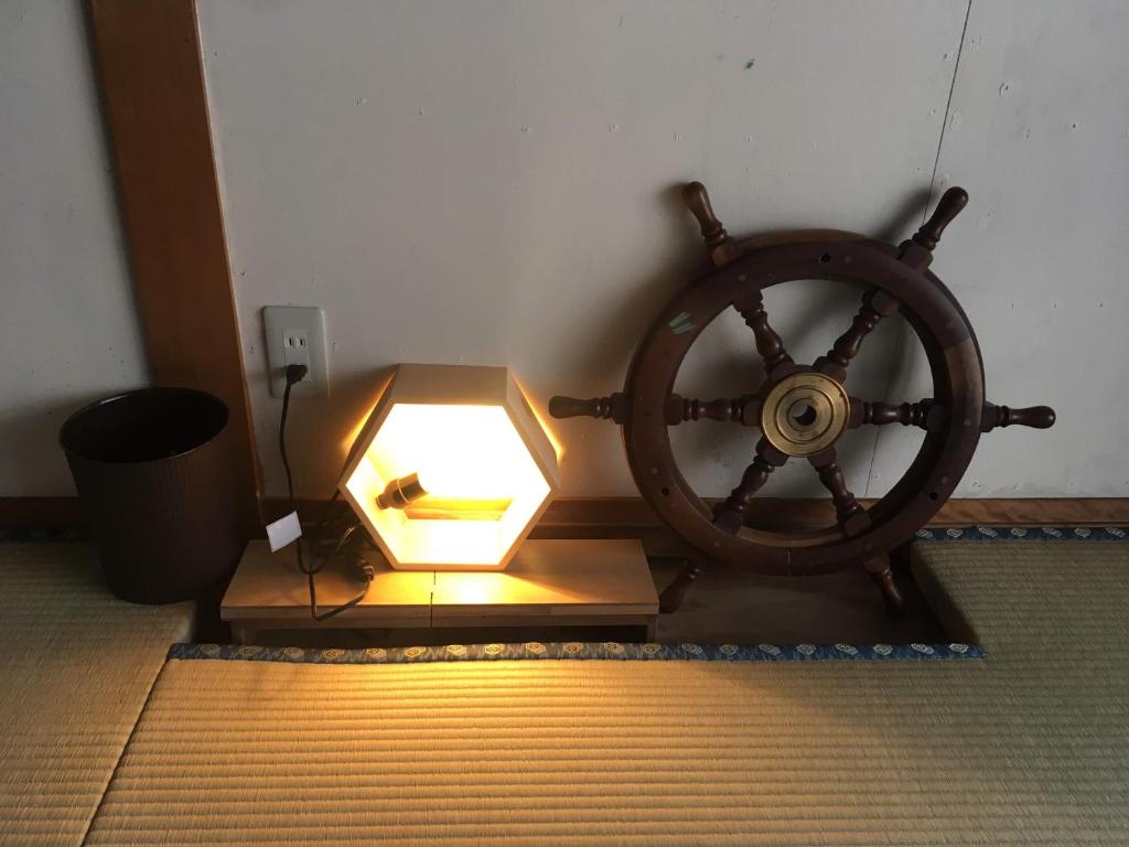 a wooden wheel and a lamp in a room at Guest House Minato in Miyako