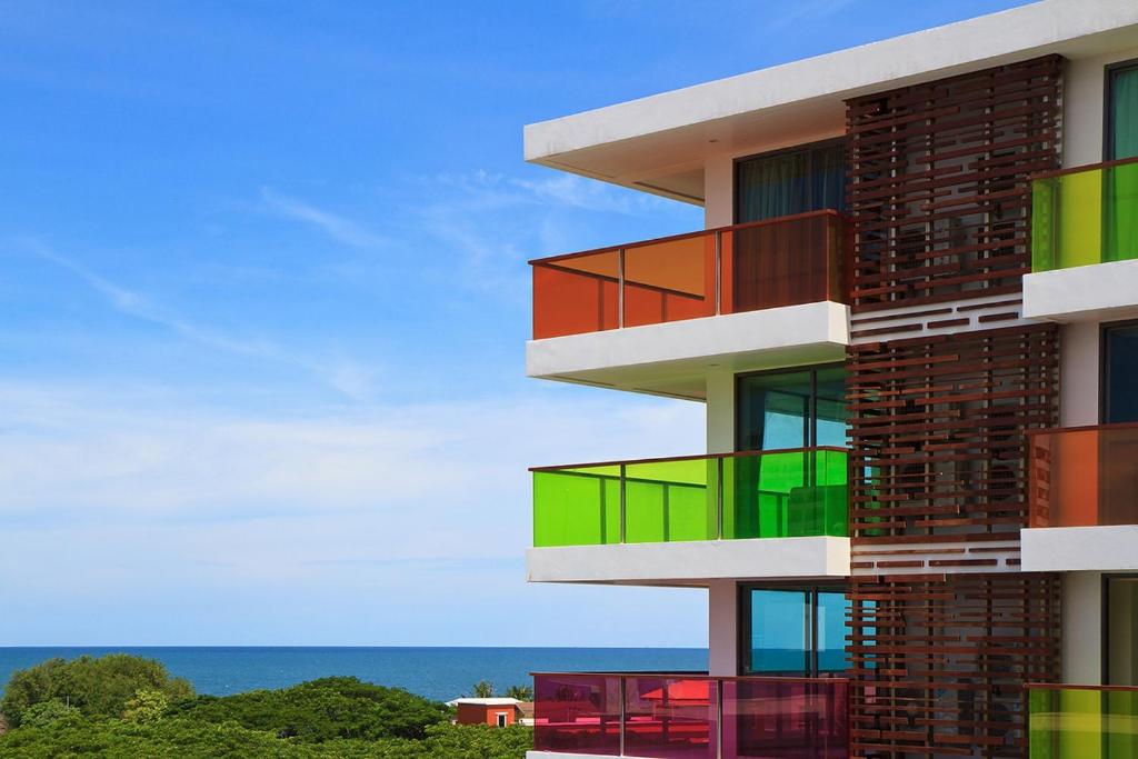 a building with colorful balconies with the ocean in the background at Rocco Hua Hin Beach Seaview in Hua Hin