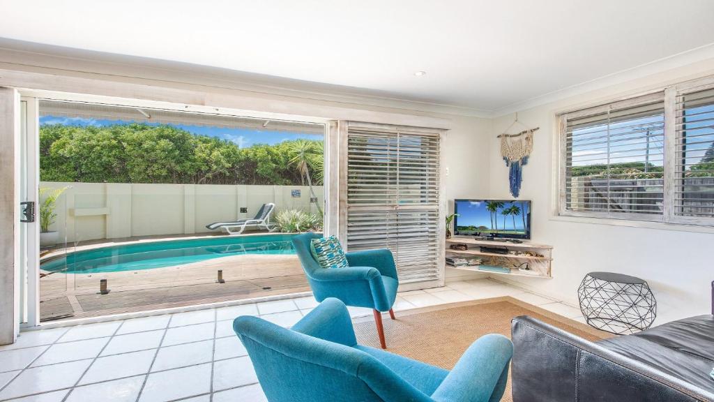 a living room with a pool and chairs and a tv at Barefoot in Lennox- Beachfront Pool in Lennox Head