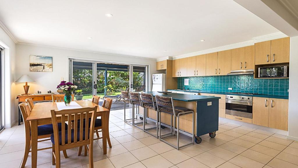 a kitchen with a table and chairs and a kitchen with blue tile at Moana Retreat in Lennox Head