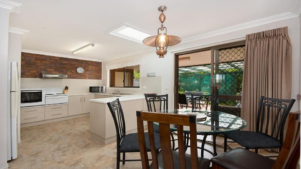 a kitchen and dining room with a table and chairs at Alexander Palms in East Ballina