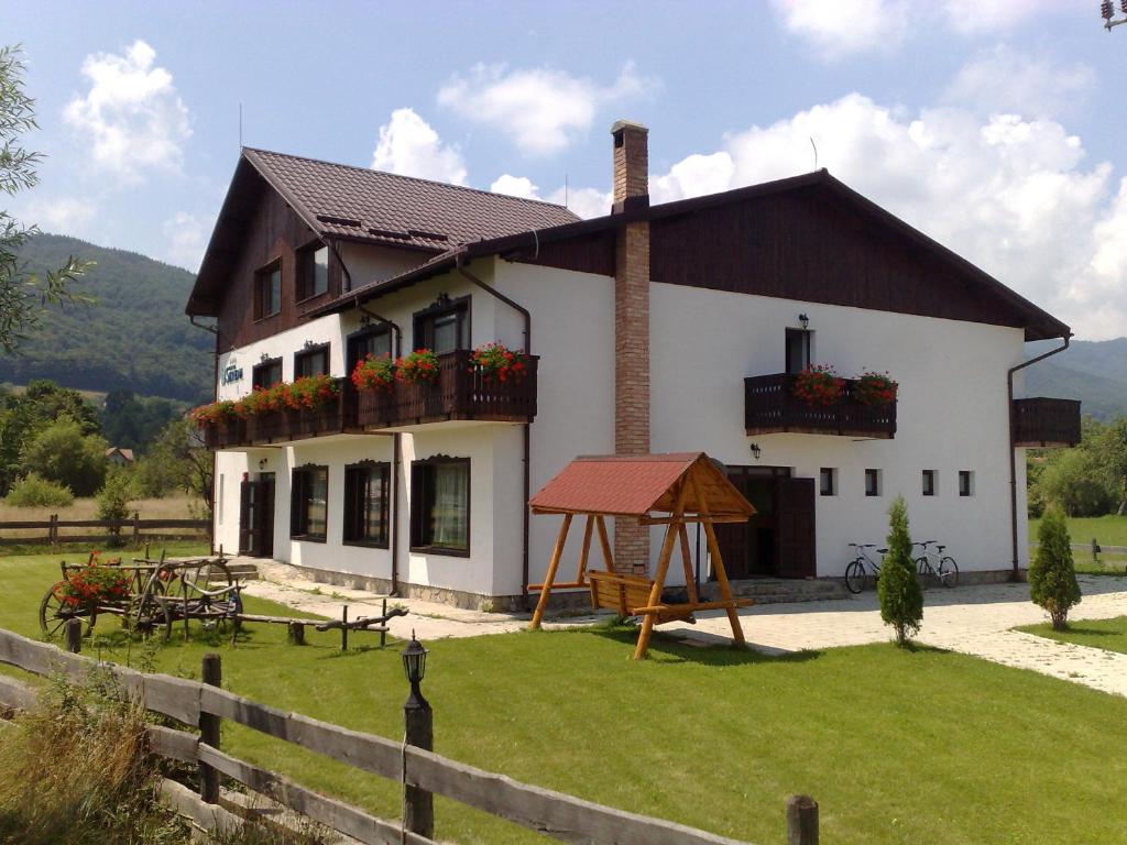 ein weißes Haus mit einem braunen Dach und einem Hof in der Unterkunft Serena Guesthouse Bran in Bran