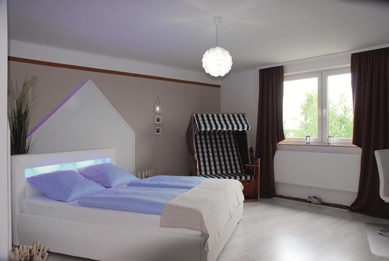 Schlafzimmer mit einem Bett mit blauer Bettwäsche und einem Fenster in der Unterkunft Hotel Rosenhof in Isenbüttel