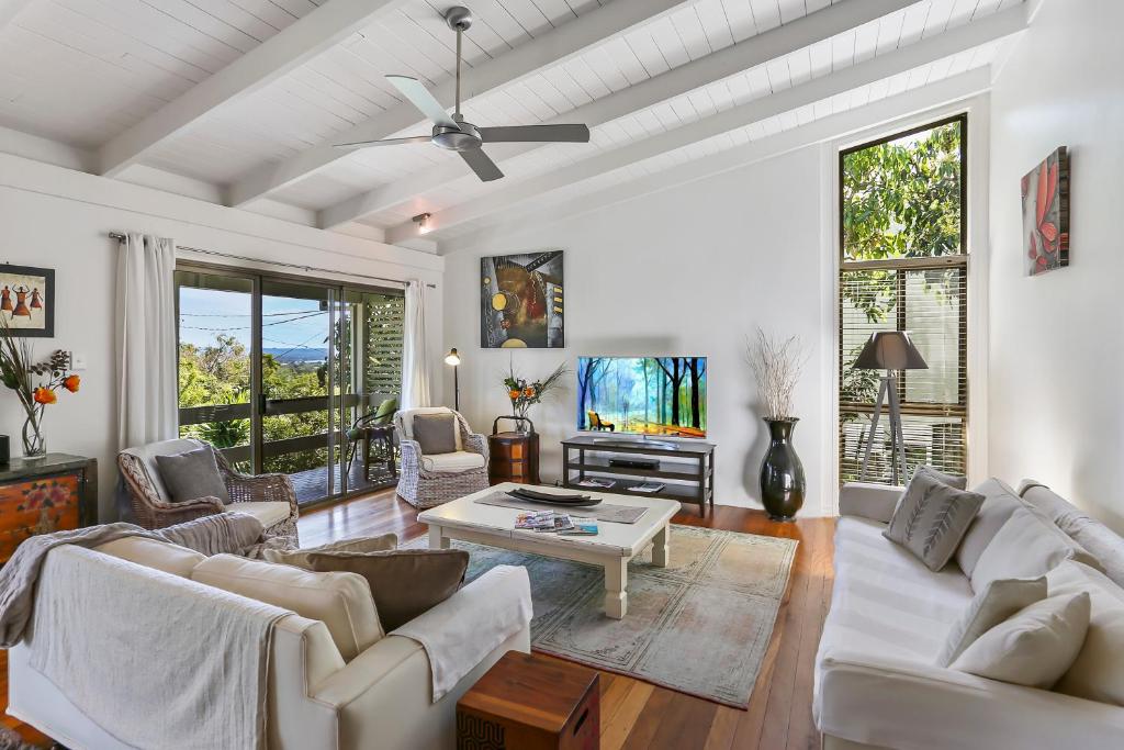 a living room with white furniture and a ceiling fan at Noosa Rest in Noosa Heads