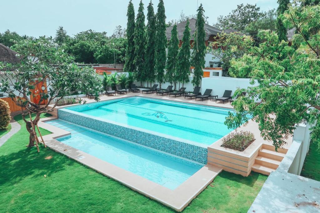 a swimming pool in a yard with trees at Liquid Dive Resort in Dauin