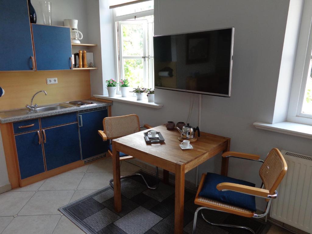 a kitchen with a wooden table and a tv on the wall at Apartment Muschel im Gästehaus Heeren in Krummhörn