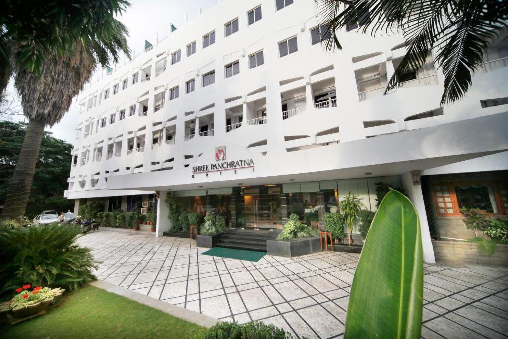 a large white building with a courtyard in front of it at Hotel Shree Panchratna Pune in Pune