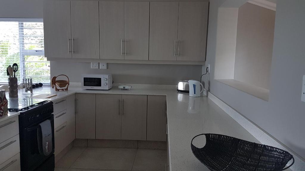 a kitchen with white cabinets and a black appliance at Barracouta Accommodation in Pennington