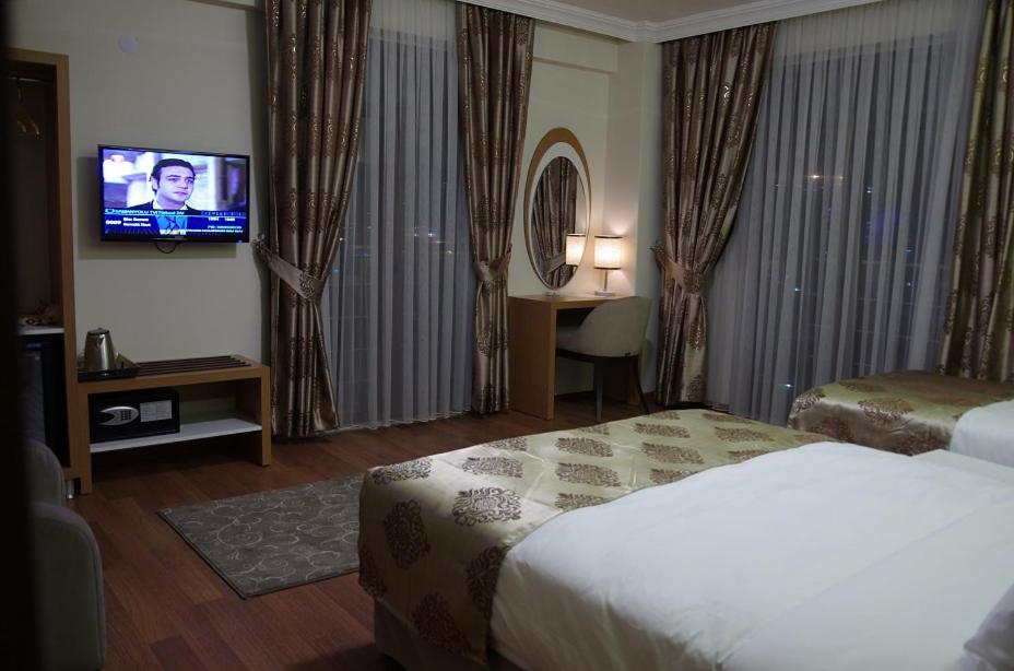 a hotel room with a bed and a flat screen tv at Gevher Hotel in Kayseri