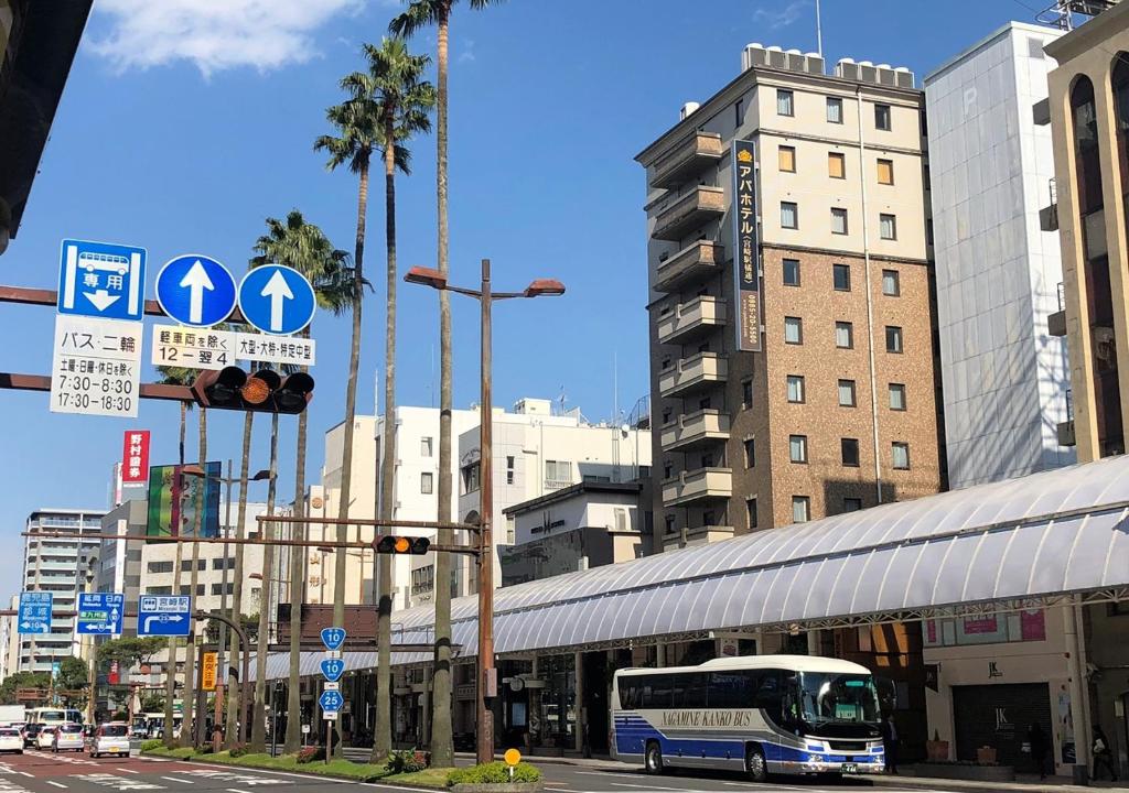 ein Bus, der in einer Stadt eine Straße entlangfährt in der Unterkunft APA Hotel Miyazaki-eki Tachibana-dori in Miyazaki