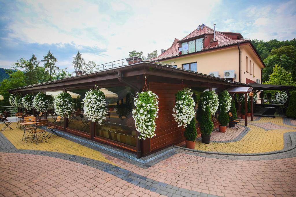 Outdoor restaurant pavilion adorned with hanging white flower baskets and patterned brick walkways.