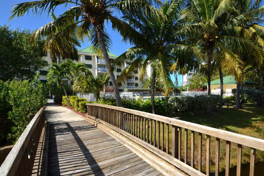a wooden walkway with palm trees and a building at Sunrise Suites Paradise Escape #407 in Key West
