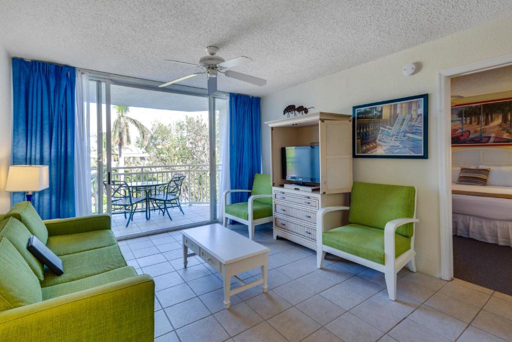 ein Wohnzimmer mit einem Sofa, Stühlen und einem TV in der Unterkunft Sunrise Suites Cat Island Suite #205 in Key West