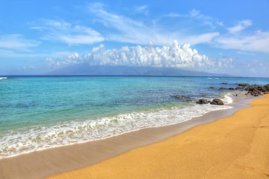 - une plage avec l'océan et un ciel nuageux dans l'établissement Valley Isle Resort, à Kahana