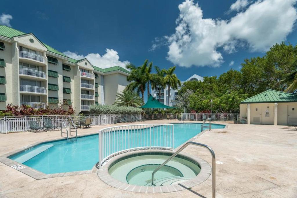 basen z krzesłami i stołami przed budynkami apartamentowymi w obiekcie Sunrise Suites Saint Croix Suite #212 w mieście Key West