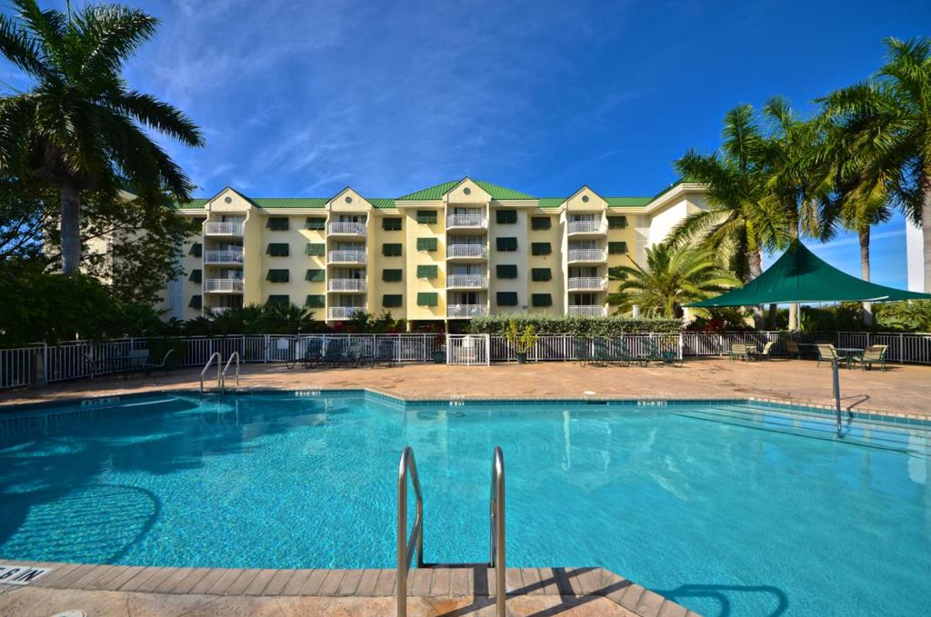 una piscina frente a un complejo con palmeras en Sunrise Suites Barbados Suite #204, en Key West