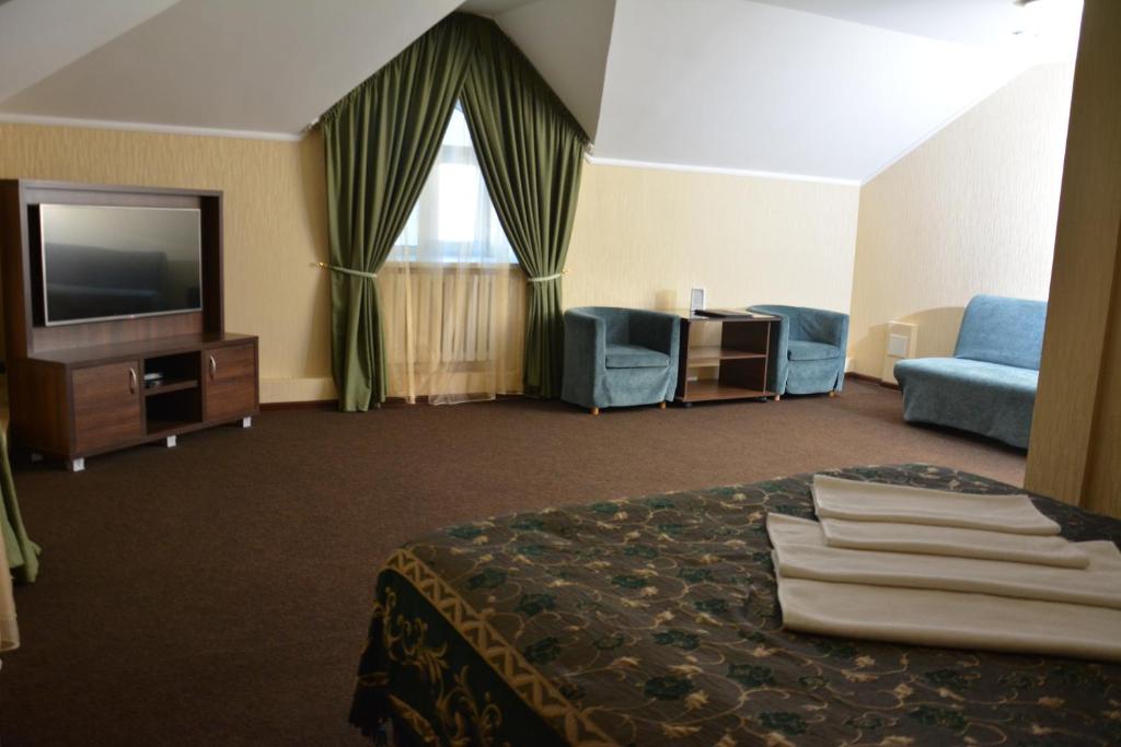a hotel room with a bed and a flat screen tv at Tropicana Inn in Uralsk