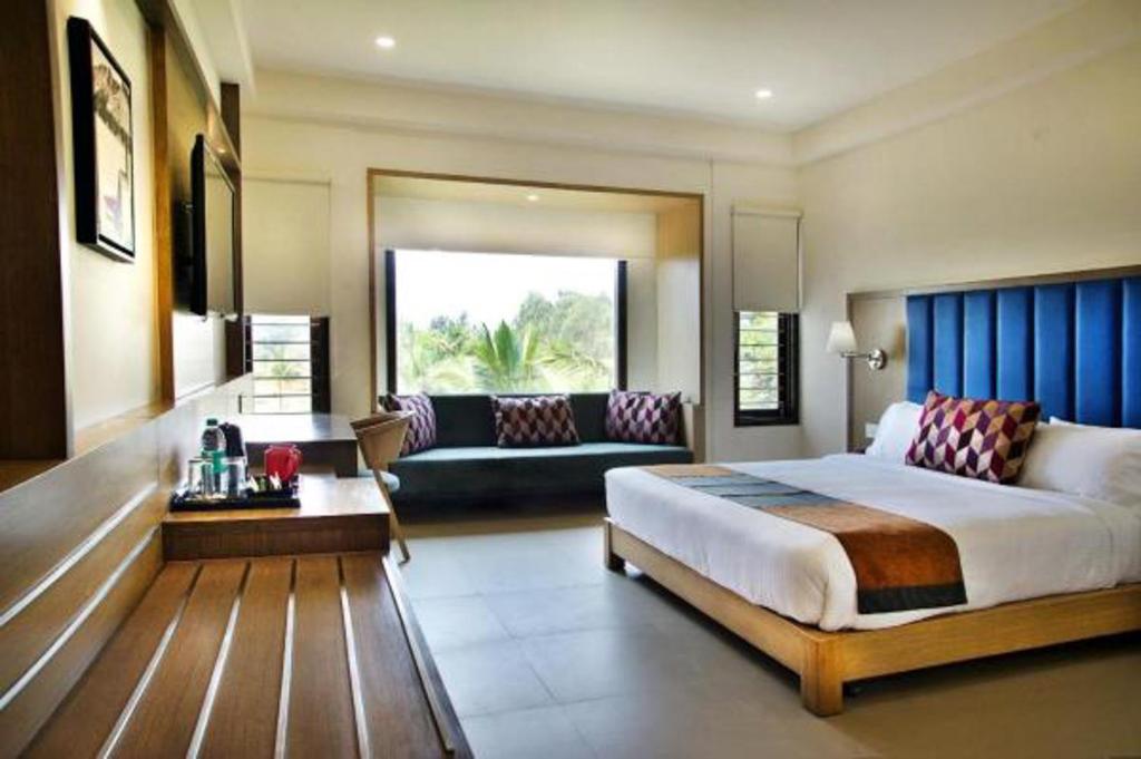 a large bedroom with a bed and a couch at Purple Cloud Hotel in Devanhalli