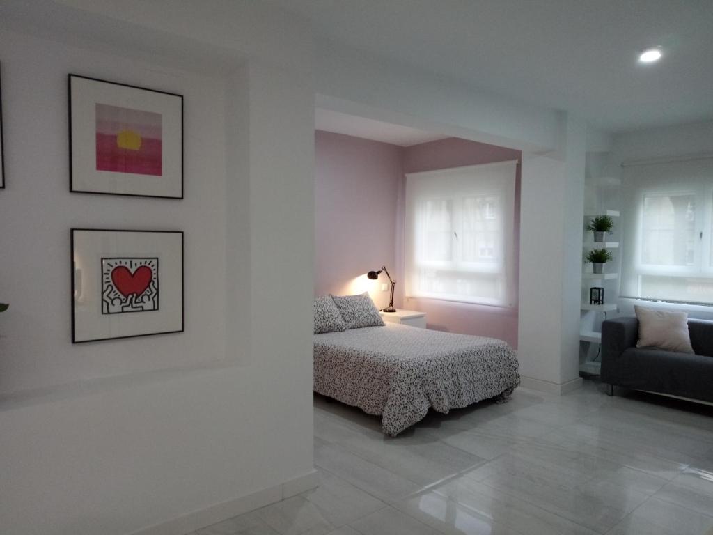 een witte slaapkamer met een bed en een bank bij Santos Studio 1 in Valencia