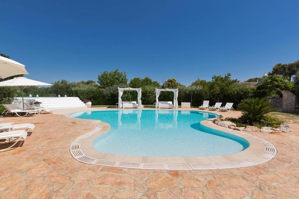 a large swimming pool with chairs in a yard at Trullo Dei Messapi in Ceglie Messapica