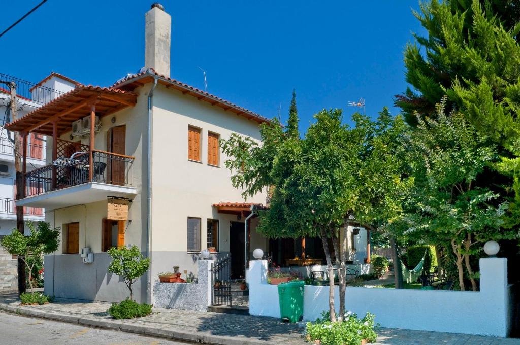 a white house with trees in front of it at Skourgias Rooms in Kala Nera