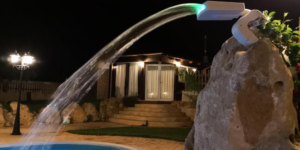 una fuente de agua frente a una casa por la noche en Country Villa en Trapani