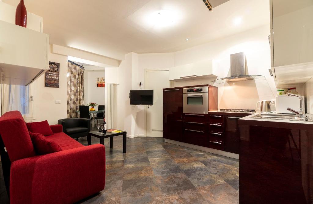 sala de estar con sofá rojo y cocina en Relax Suite Nazario, en Bolonia