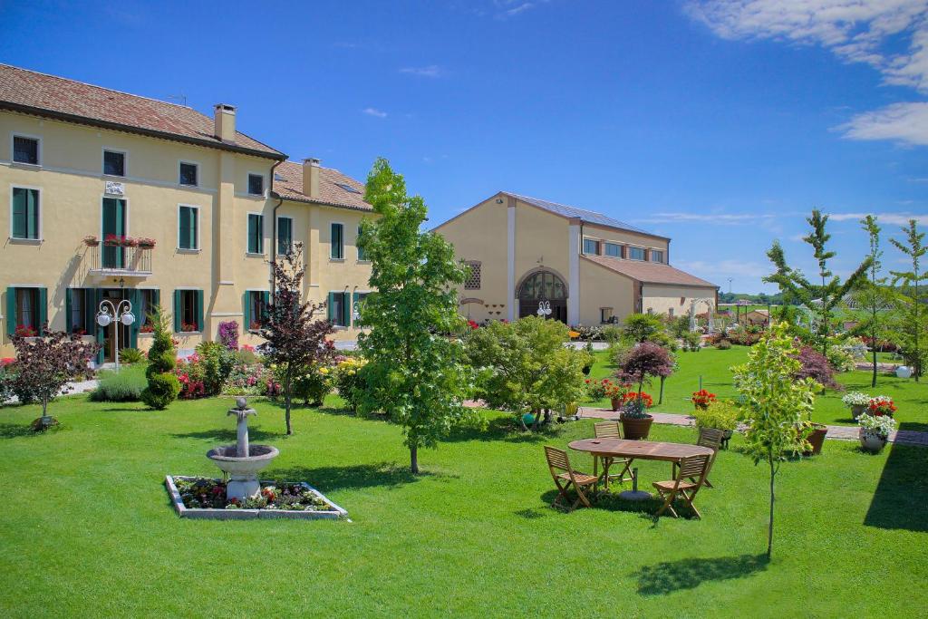 a garden with a table and a fountain in front of a building at Millefiori la Corte delle Rose in Rovigo