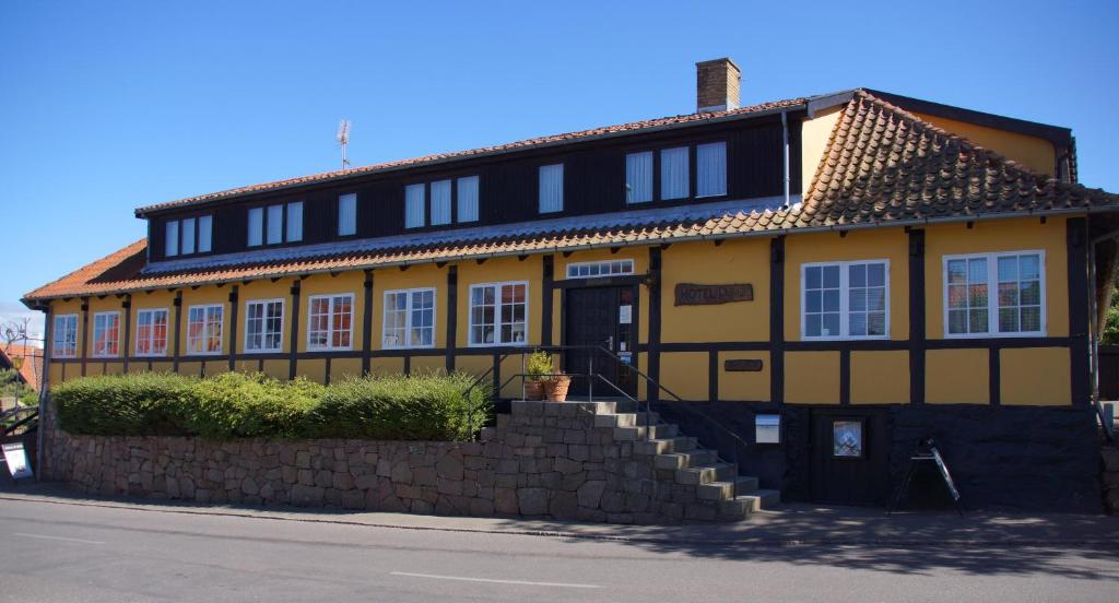 un edificio amarillo y negro al lado de una calle en Hotel Pepita, en Allinge