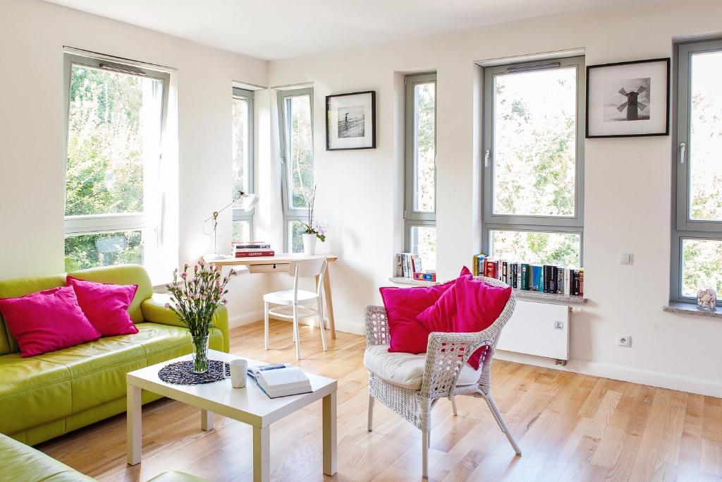 a living room with a green couch and pink pillows at Apartamenty Bałtycka by Renters in Świnoujście