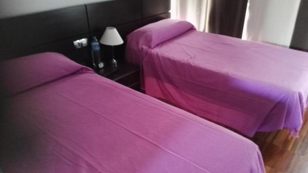 two beds in a room with purple sheets at albergue rural vía de la plata in Casar de Cáceres