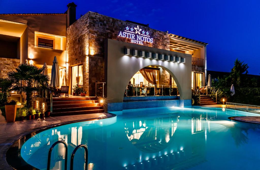 a swimming pool in front of a building at night at Astir Notos in Potos