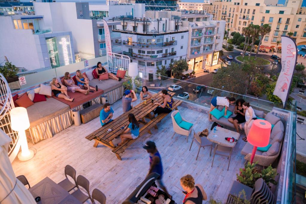 a group of people sitting on the rooftop of a building at Marco Polo Party Hostel in St. Julianʼs