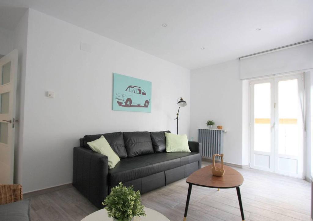 ein Wohnzimmer mit einem schwarzen Sofa und einem Tisch in der Unterkunft Apartamento entero 4HB centro Salamanca by Batuecas in Salamanca