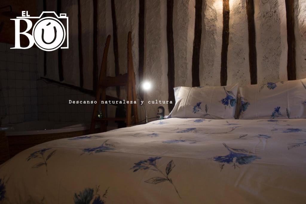 Un dormitorio con una cama con flores azules. en El Bú, en Peralejos de las Truchas
