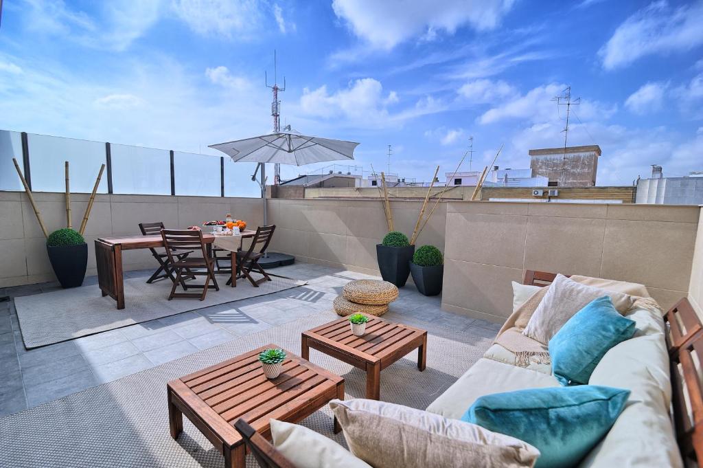 eine Terrasse mit einem Sofa und Tischen auf dem Dach in der Unterkunft HQ Rooms Apartments San Vicente in Valencia