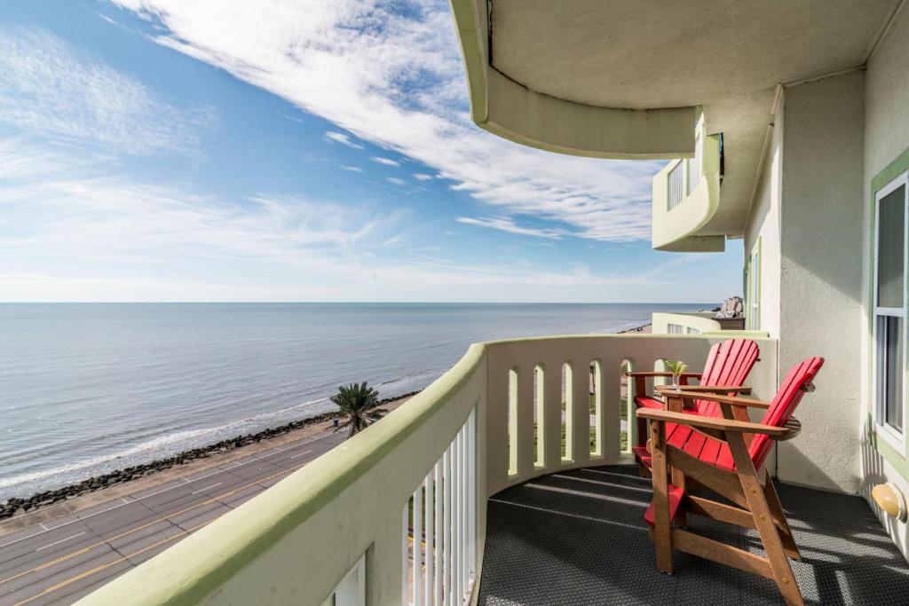 einen Balkon mit zwei roten Stühlen und Meerblick in der Unterkunft Sea Deuce by the Ocean in Galveston